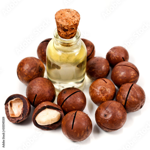 Macadamia nuts heap and macadamia oil in glass bottle isolated on a white background.