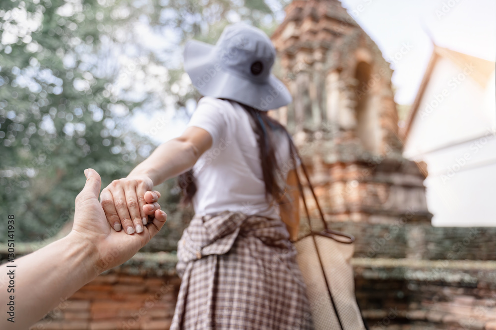 Woman wanting her man to follow her in old temple. View from behind. (focus on hands). Asian couple travel concept