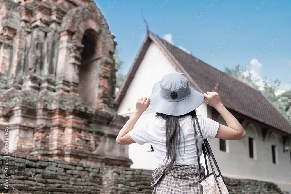 Young woman traveler traveling in old temple. View from behind. Asian tourist concept