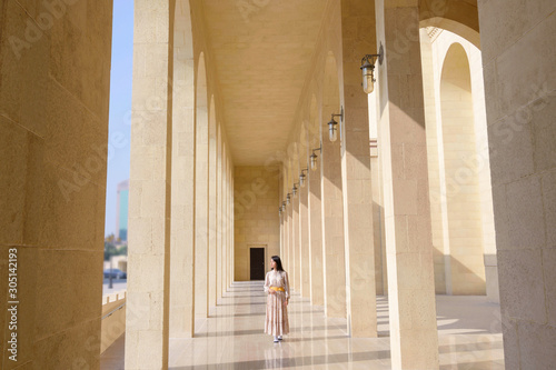 Asian traveller woman walking on perspective of the building with morning sunlight and shadow on floor background, Bahrain
