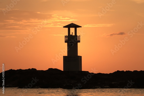 Silhouette of a lighthouse during sunset on a beach