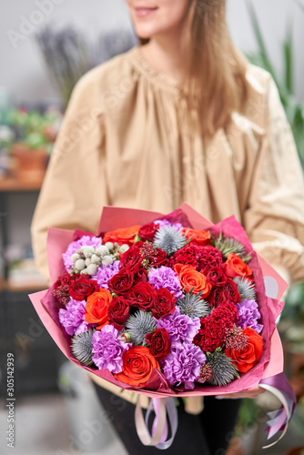 Modern floral shop. Finished work of the florist. Cute bouquet of mixed flowers in womans hands. Delivery fresh cut flower from online store