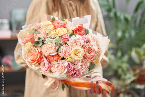 Modern floral shop. Finished work of the florist. Cute bouquet of mixed flowers in womans hands. Delivery fresh cut flower.