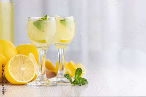 Alcohol cocktail drink with lemon, mint and ice in a small glass. photo