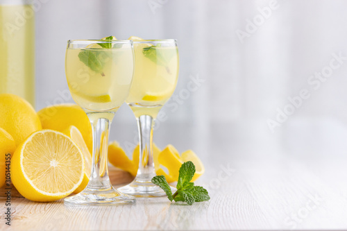 Billede på lærred Alcohol cocktail drink with lemon, mint and ice in a small glass.