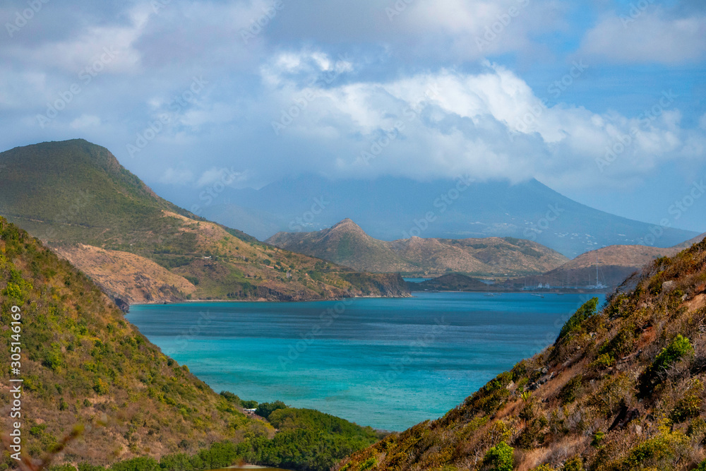 The Caribbean Sea is seen between a couple mountains on the tropical island of St. Kitts 