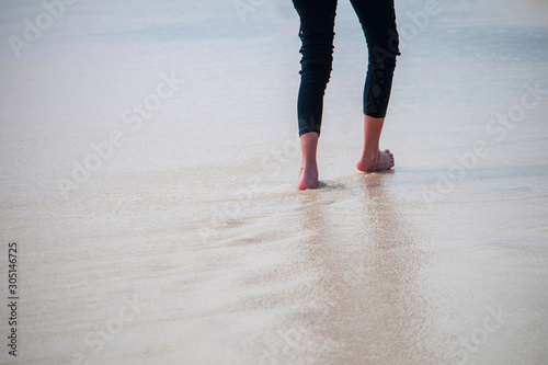 Young girl walking on the beach in the wet sand after a wave soaked the sand. 