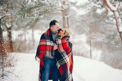 Adult5 couple walking in a winter park. Man and woman have fun with snow. Pair with red blanket