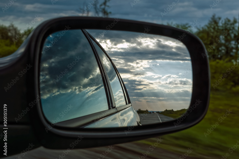view from a car mirror on a stormy sky