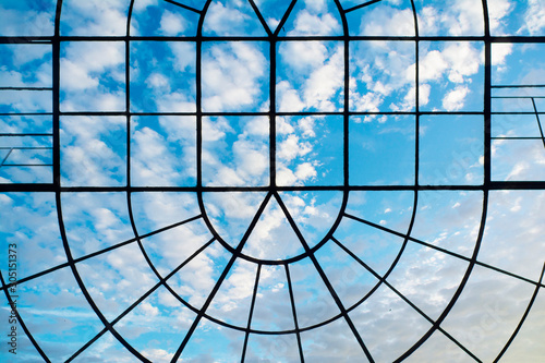 Ceiling with decorative grid roof with blue sky and clouds.