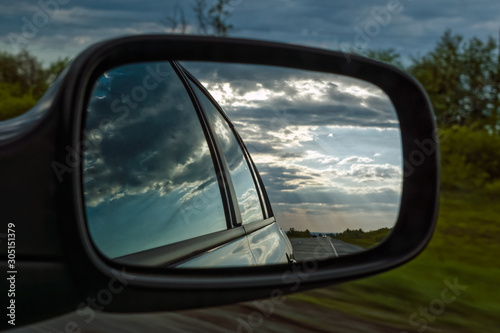 view from a car mirror on a stormy sky