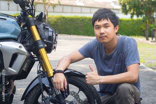 Attractive guy in t-shirt is looking at camera and smiling while sitting on the motorcycle. Motorcycle smile.