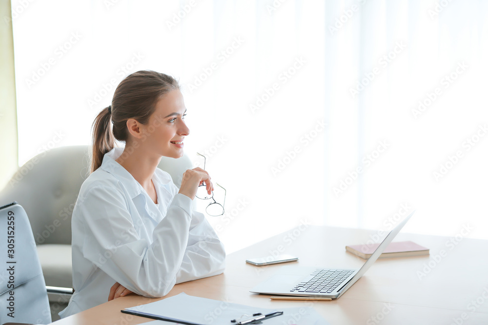 Female doctor with laptop sitting at table in clinic Female doctor with laptop sitting at table in clinic