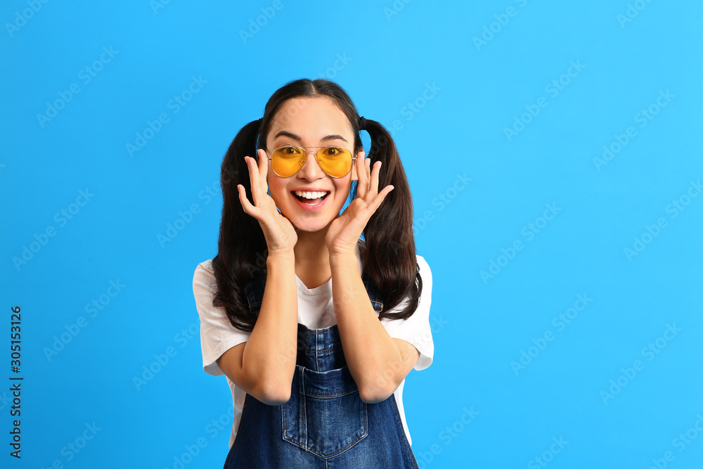 Stylish young Asian woman on color background
