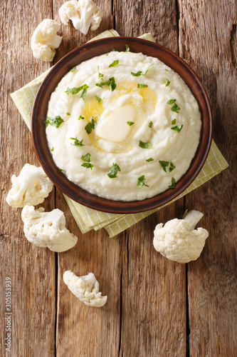 Dietary delicious cauliflower puree with butter and parsley close-up on a plate. Vertical top view