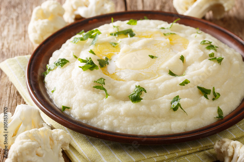 Homemade mashed cauliflower with butter and parsley close-up on a plate on the table. horizontal photo