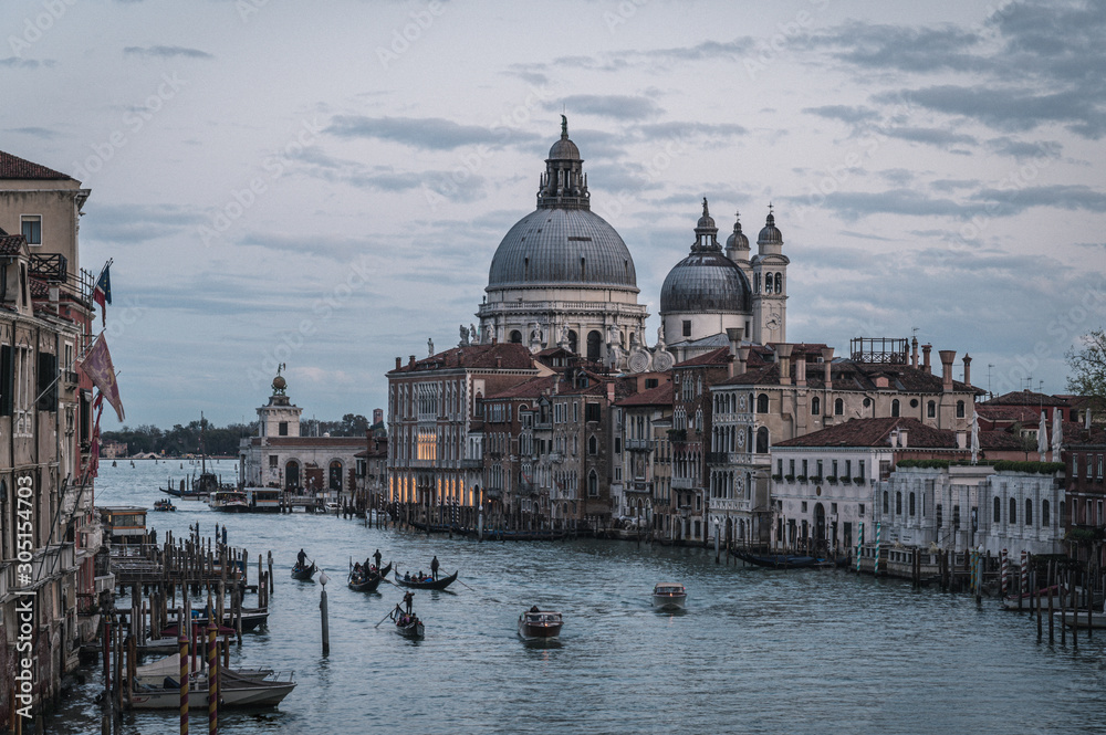 Venice Grand canal on sunset time. View of Basilica di Santa Maria della Salute, gondolas, water buses and typical Venetian houses and architecture. Beautiful and romantic Italian city.