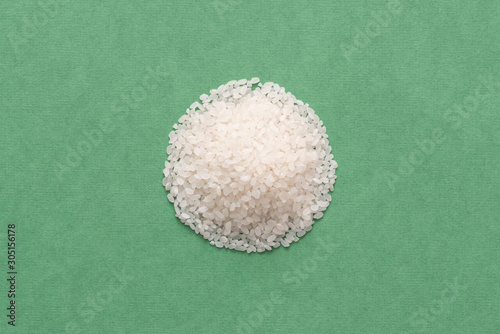 Heap of raw rice isolated on green background. photo