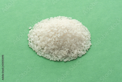 Heap of raw rice isolated on green background. photo