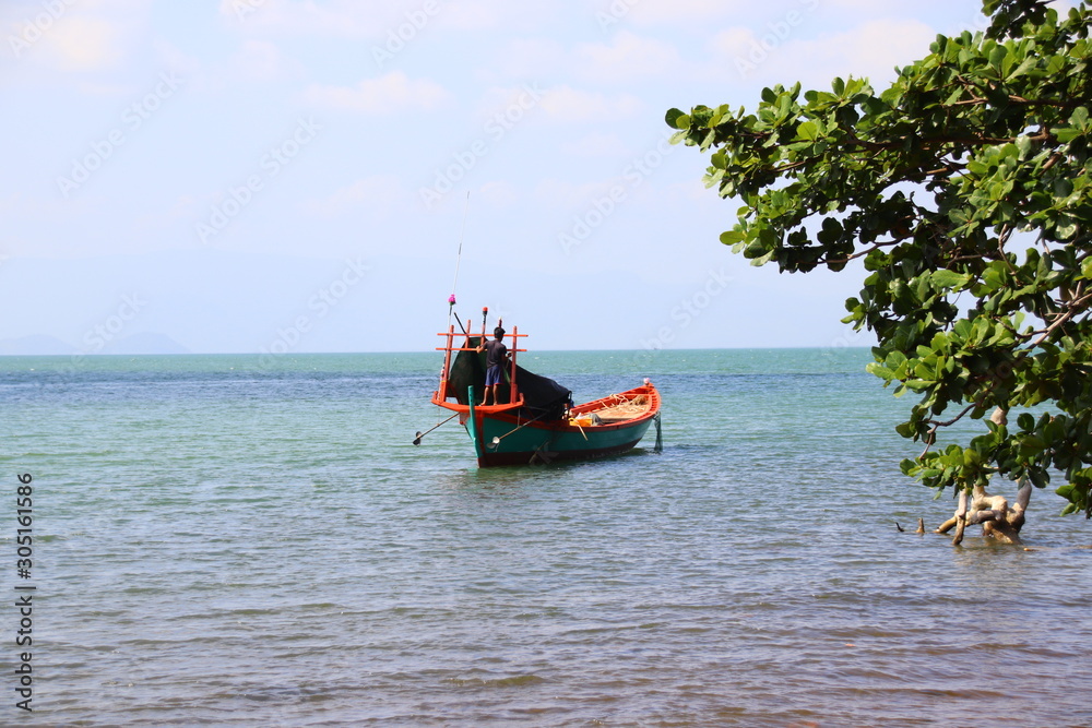 Moored traditional khmer fishing boat in the sunny coast, showing a candid summer moment and daily life in Kep Cambodia Moored traditional khmer fishing boat in the sunny coast, showing a candid summer moment and daily life in Kep Cambodia