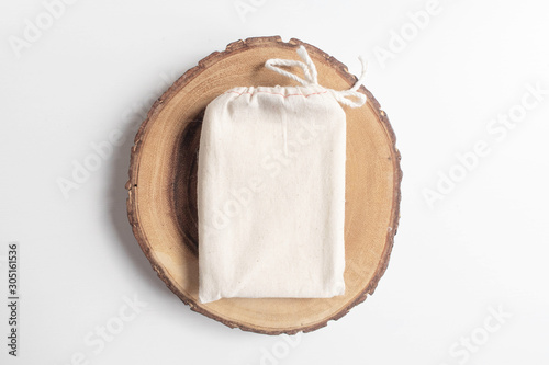 Mock up of cotton bag or pouch on wooden cut tree section on white table. Boho design of tarot cards deck pouch on white table with copy space for your image or text