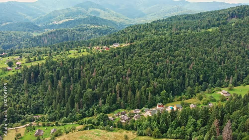 Aerial view of mountain range, road, and fir forest with village houses. View from above. Aerial view of mountain range, road, and fir forest with village houses. View from above.