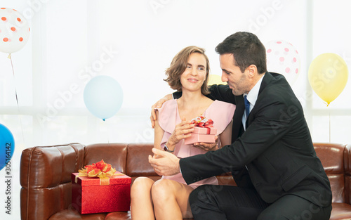 Beautiful young couple is celebrating at home. Handsome man is giving his girlfriend a gift box. Man giving a christmas present to his girlfriend