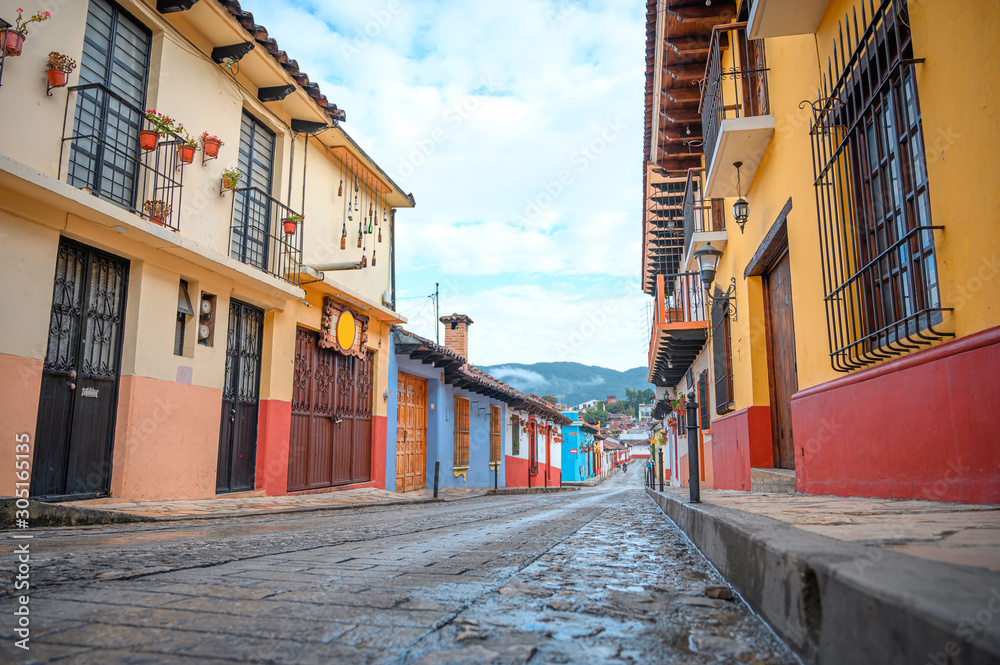 Colorful street of a Mexican town San Cristobal De Las Casas in Chiapas, in the background wooded mountains and a cloudy sky Colorful street of a Mexican town San Cristobal De Las Casas in Chiapas, in the background wooded mountains and a cloudy sky