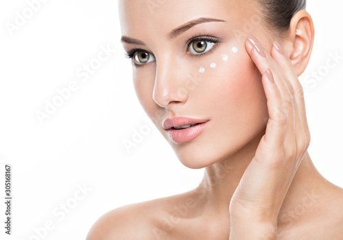 woman with healthy face applying cosmetic cream under the eyes