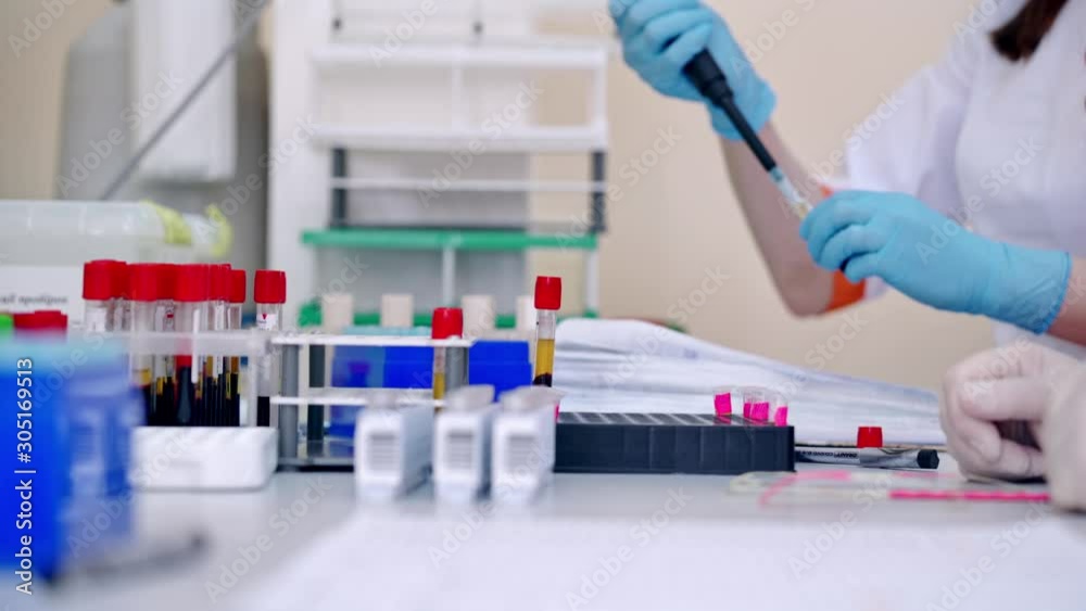Lab technician holding blood tube sample for study. Medical technologist dropping blood into test tube in hospital laboratory Lab technician holding blood tube sample for study. Medical technologist dropping blood into test tube in hospital laboratory