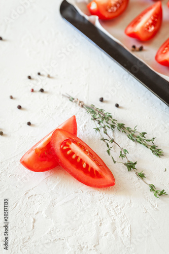 Fresh red, ripe tomatoes in bowl with herbs on a light background. Juicy tomato vegetables 