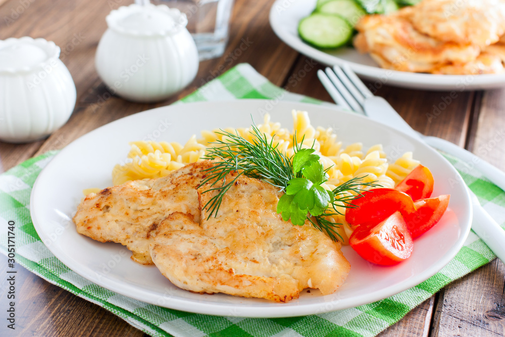 Chicken breast in batter with pasta on a white plate, selective focus