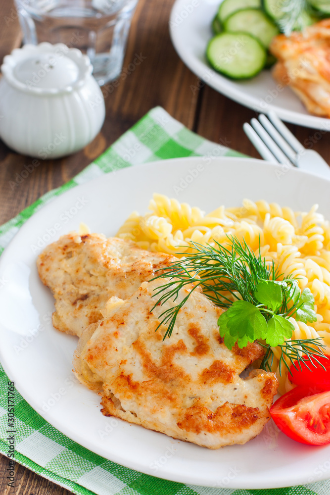 Chicken breast in batter with pasta on a white plate, selective focus Chicken breast in batter with pasta on a white plate, selective focus