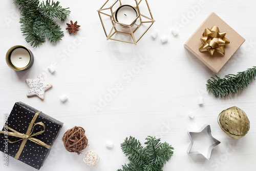 White wood background with christmas decor: gifts, fir branch, candles, top view