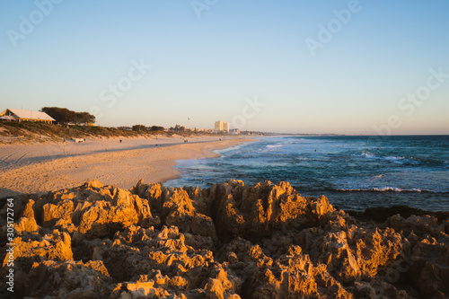 The beautiful view of Trigg beach at sunset over the jagged rocks, ocean and beach on a lovely evening in Perth, Western Australia. 