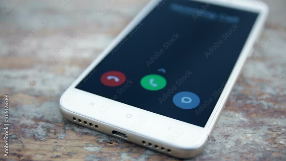 Incoming call on white mobile phone on wooden surface