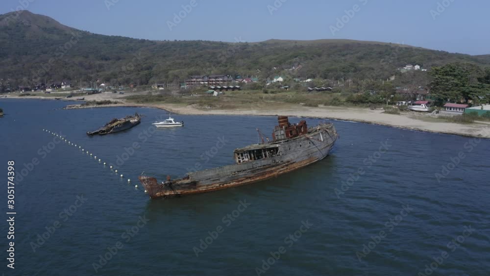 Ships graveyard. Two derelict partially submerged shipwreck, aground near the shore. Aerial descent shot. Ships graveyard. Two derelict partially submerged shipwreck, aground near the shore. Aerial descent shot.