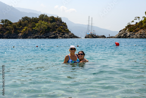Women are posing in shallow water of Oludeniz beach, Turkey. © vaz1