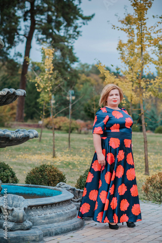 Middle age woman of plus size, American or European appearance walks in the city enjoying life. Lady with excess weight, stylishly dressed at the center of the city. Natural beauty