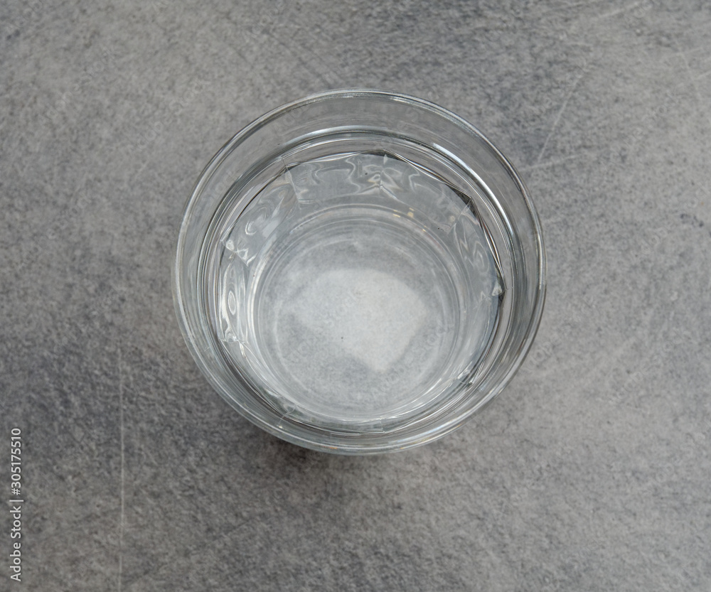 crystal clear glass of water on grey marble table background, top view