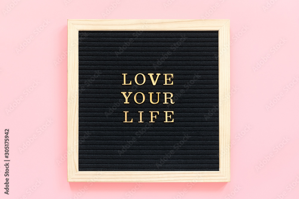 Fototapeta Love your life. Motivational quote in gold letters on black letter board on pink background, central composition . Top view Flat lay Copy space Concept inspirational quote of the day