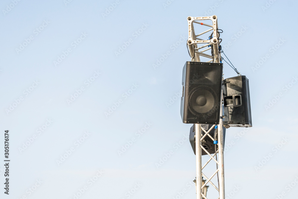 a bunch of digital woofer loud speaker are hanging on the hanger at an open music concert a bunch of digital woofer loud speaker are hanging on the hanger at an open music concert