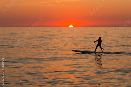 paddle standing board, beach leisure activity, beautiful silhouette of man at sunset. Romantic colorful sunset at the sea. Sun go down © siyatsky