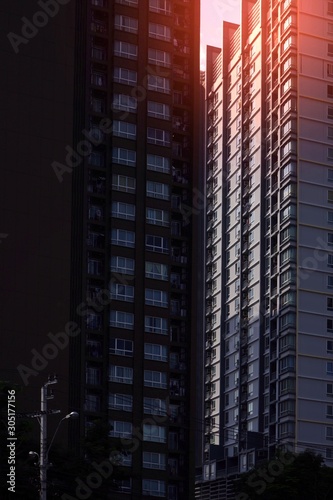 Flare light and shadow on surface of the large residential condominiums in dark tone style, low angle view and vertical frame 