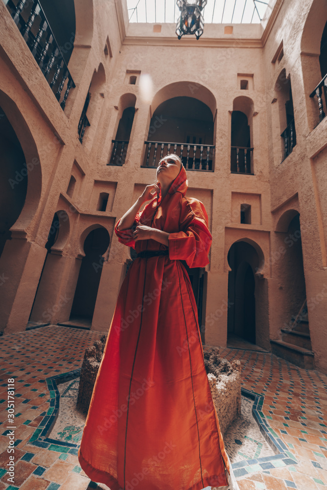 girl in the temple of morocco stands in the middle in a dress with a hood