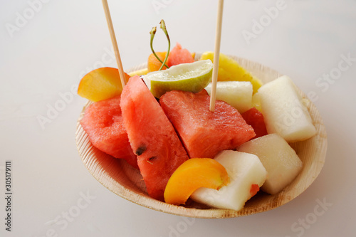 Bamboo plate with seasonal fruit. Watermelon, melon, apricot, lime, pear. Refreshing. Vegetarian diet concept.