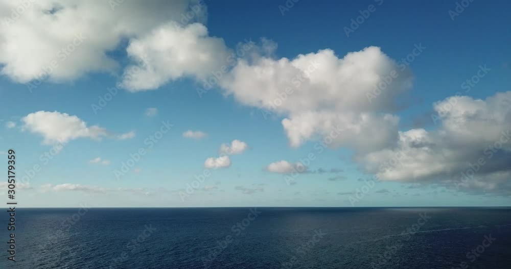 Drone shot of blue sky with white clouds panning down to reveal ocean horizon Drone shot of blue sky with white clouds panning down to reveal ocean horizon