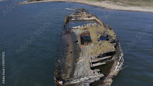 Ships graveyard. A pass along the hull of derelict partially submerged shipwreck in the afternoon. Aerial dolly shot. photo