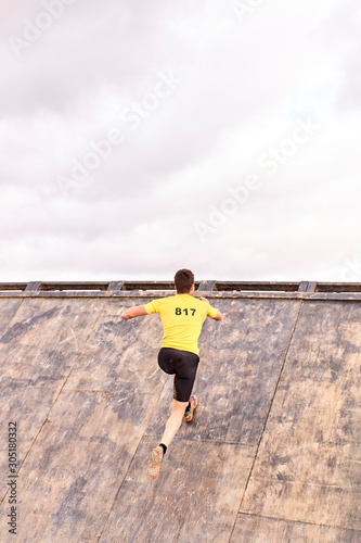 young man climbing a wooden wall in a Spartan race