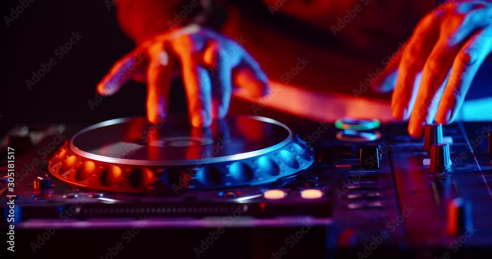 Disc jockey working on his professional mixer controller, sliding the panels and turning knobs in nightclub red and blue lights - nightlife concept 4k footage close up shot